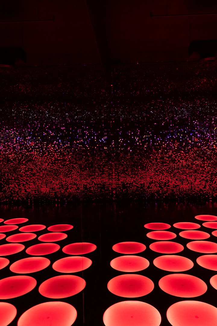 red led circle lights on the floor of a dark room at the color factory nyc