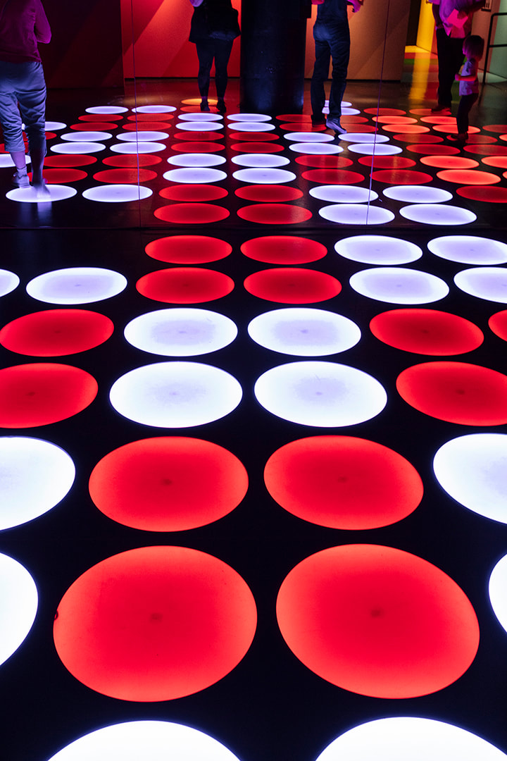 red and white led circle lights on the floor of a dark room at the color factory nyc